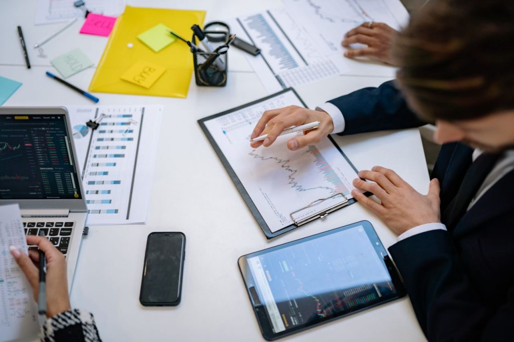 a-businessman-reviewing-business-analytics-7693686 Team reviewing financial charts and digital data on tablets in an office setting.
