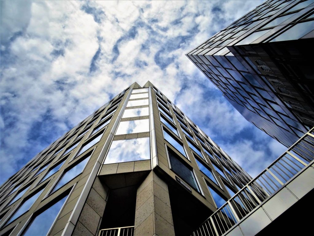 Low angle view of modern skyscraper with glass facade reflecting the sky.